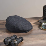 Men's black herringbone gatsby cap on table